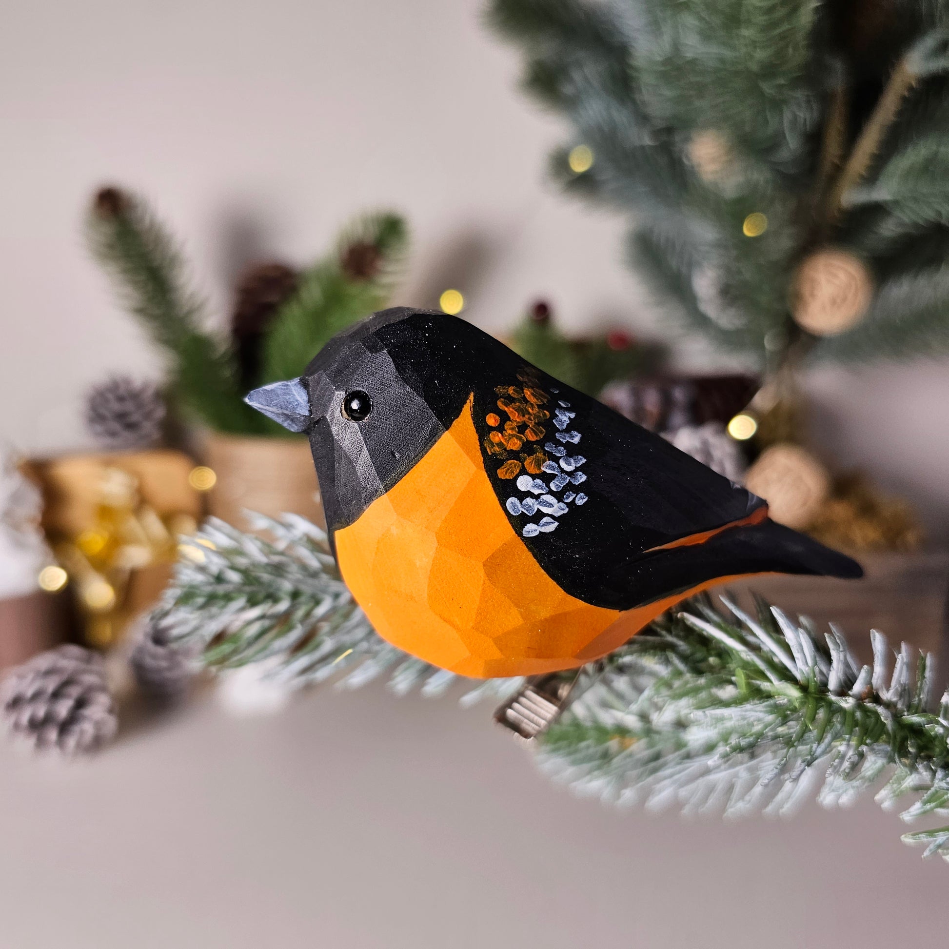 Hand-carved Baltimore Oriole clip-on bird ornament in solid basswood, showing vivid hand-painted flame-orange plumage and black hood with integrated metal clip