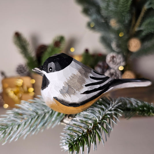 Hand-carved solid basswood Black-capped Chickadee clip-on ornament showing black cap, white cheeks, and buff flanks — by Painted Bird Shop.