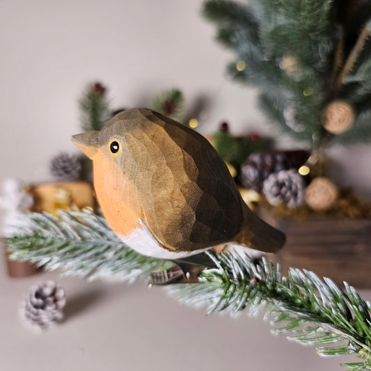 Hand-carved solid basswood European Robin clip-on ornament perched on a pine branch, showing flame-orange breast and hand-painted brown plumage detail