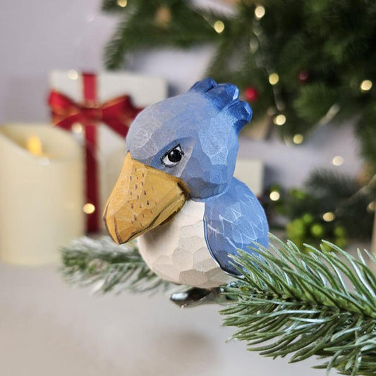 Hand-carved solid basswood Shoebill clip-on bird ornament with slate-blue plumage and distinctive hook-tipped bill, displayed on a pine branch
