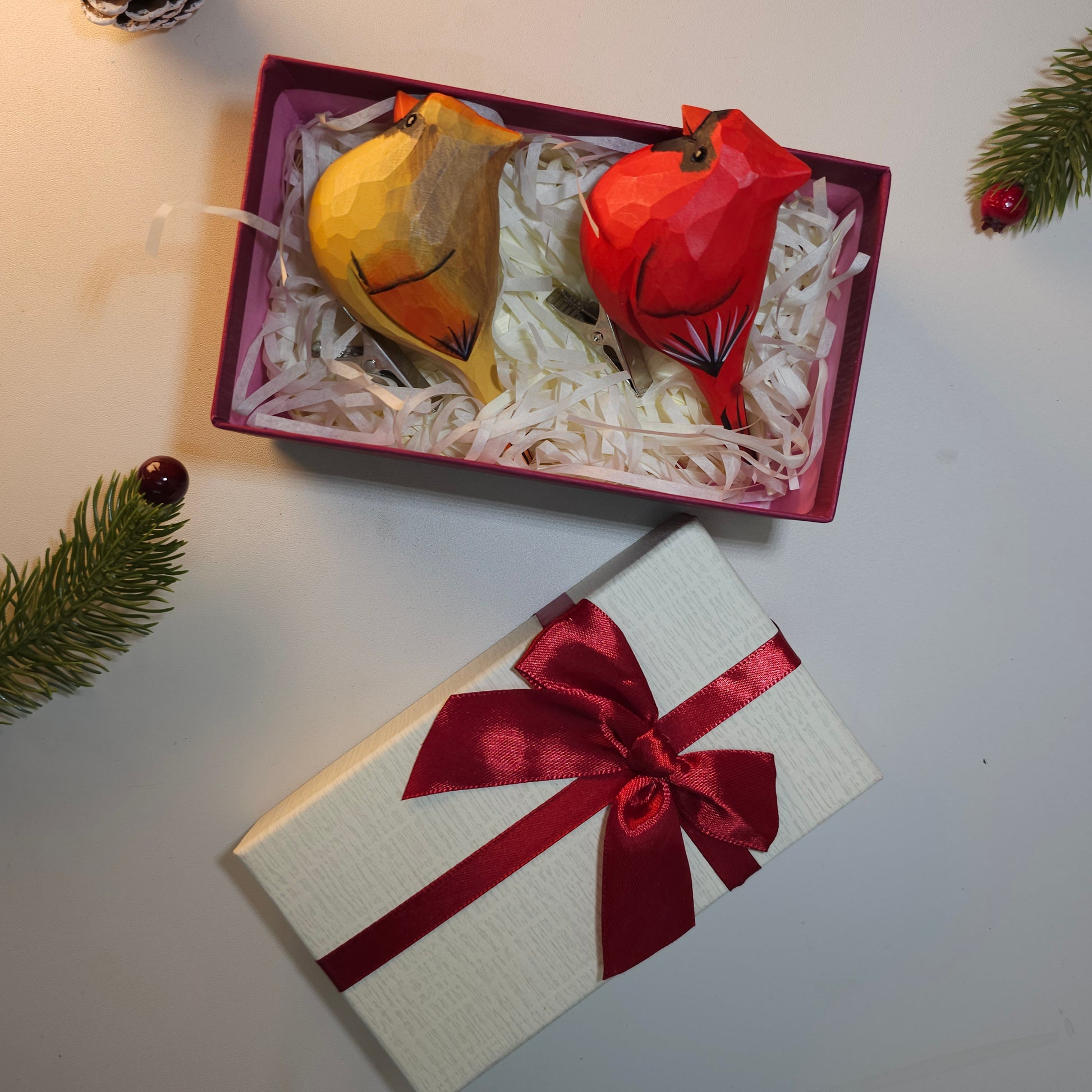 Hand-carved wooden Northern Cardinal ornaments in gold and red, presented in a gift box with a ribbon.